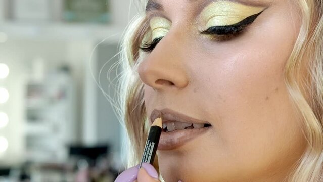 professional make-up artist makes a bright evening make-up, the master uses a cosmetic lip pencil.