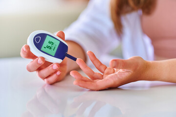 Female using glucose meter for measuring and monitoring blood level. Healthcare and mellitus diabetes treatment