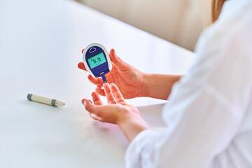 Female using glucose meter for measuring and monitoring blood level. Healthcare and mellitus diabetes treatment - obrazy, fototapety, plakaty