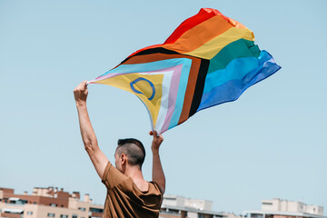 waves a progress pride flag in the air - 514203158