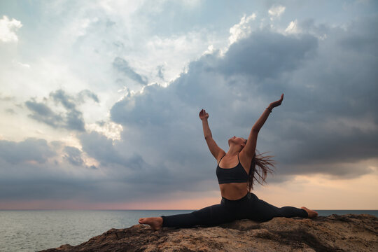 Young woman does asana yoga for healthy lifestyle on tropical coast beach at sunset.
