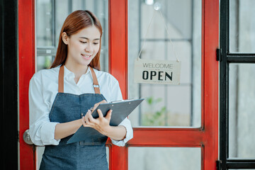 Happy young Asian business owner woman standing with open sign board