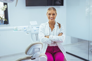 Fototapeta premium People, medicine, stomatology and healthcare concept - happy young female dentist with tools over medical office background. Portrait of female dentist smiling with arms crossed in dental clinic