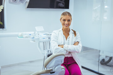 Young female dentist in white coat at workplace. Space for text. Portrait of young female dentist...
