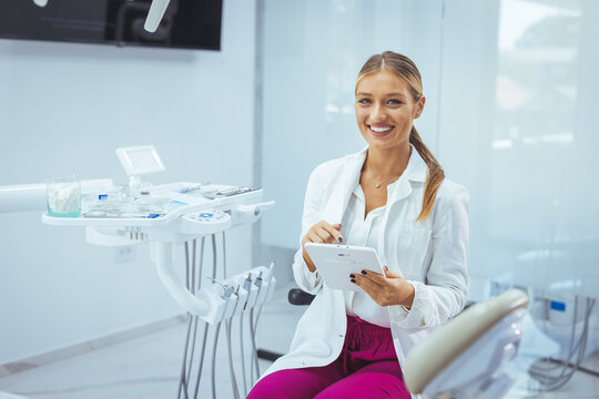 Portrait Of Beautiful Professional Female Stomatologist Posing In Clinic Interior, Happy Dentist Lady Standing With Folded Arms And Smiling At Camera, Ready For Check Up