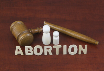 Wrong court laws about abortion concept. Letters abortion with broken judge gavel and figures of...