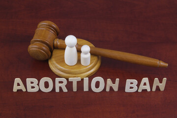 Laws about ban abortion concept. Letters abortion ban with judge gavel and figures of female and...