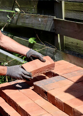 Man's hand holding red brick. Construction and building works concept. House renovation in process. 