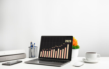 Laptop is graph displayed on the desk in the office and has Smartphone, and coffee cup. The concept of business, finance, banking, and interest is booming. Copy space on top for design, Closeup, 202