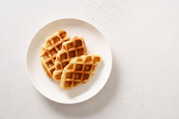 Trendy delicious croffles on white plate on a white background. Croissant as waffle. View from above. Copy space.