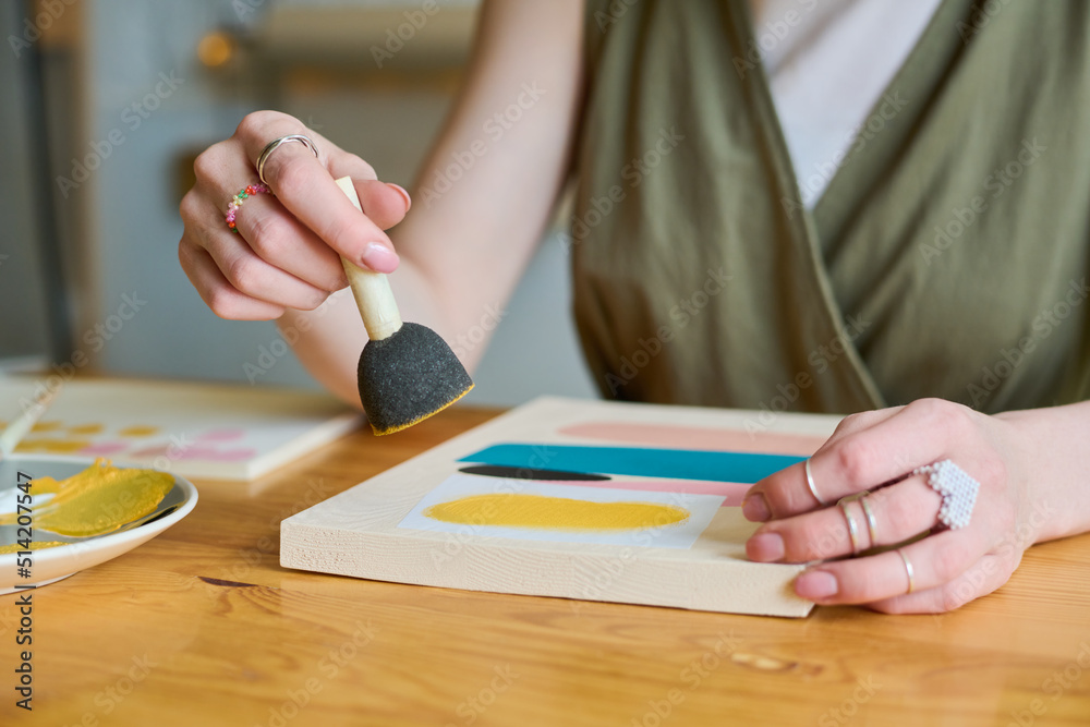Aufkleber hands of young creative woman holding sponge for applying gouache over paper while working over new 
