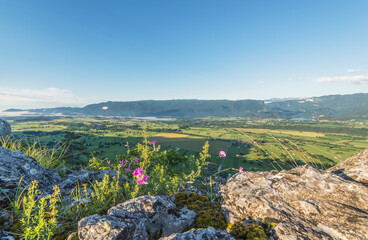 Man standing at the top of the hill and taking photos of the picturesque valley below. Vivid colors of the meadows and fields.