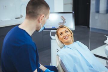 European young woman sitting in medical chair while dentist fixing her teeth at dental clinic....