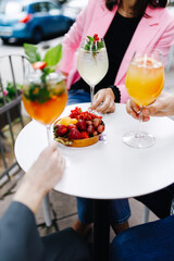 friends are drinking cocktails at a white table