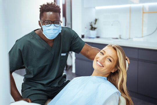 The woman came to see the dentist. She sits in the dental chair. The dentist bent over her. Happy patient and dentist concept. Amazing smile!