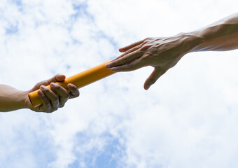 Close up hand set baton from hand to hand on sky background. Business concept for teamwork and team...