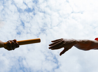 Close up hand set baton from hand to hand on sky background. Business concept for teamwork and team...
