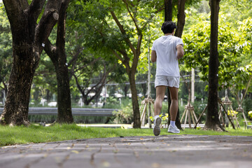 Asian handsome man in white shirt running in park. Concept for health lifestyle in park.