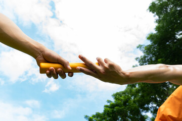 Close up hand set baton from hand to hand on sky background. Business concept for teamwork and team...