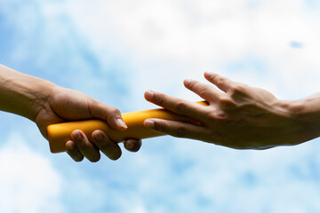 Close up hand set baton from hand to hand on sky background. Business concept for teamwork and team builder. - obrazy, fototapety, plakaty