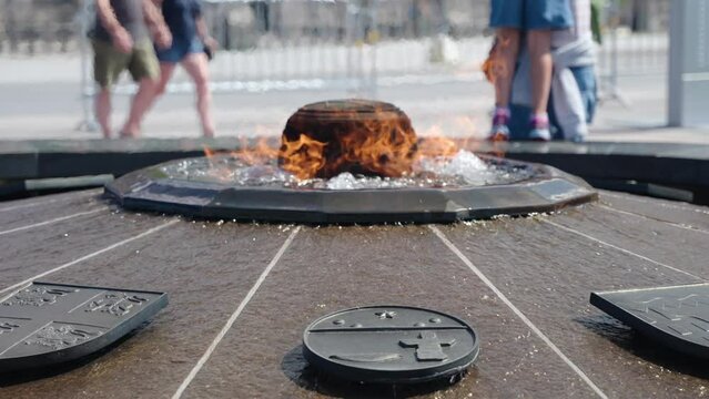 Centennial Flame on Parliament Hill, Ottawa, Canada on a sunny day with tourists walking around in the background - 4K slow motion