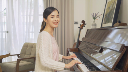 An Asian woman musician playing and practicing piano song at home or house for party music...