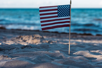 There is an American flag on the beach on the sand. A symbol of freedom. Patriotism. July 4th...