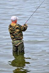 A man is fishing with a spinning rod on a summer day