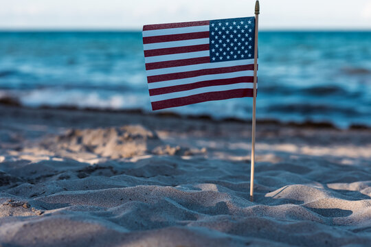 There is an American flag on the beach on the sand. A symbol of freedom. Patriotism. July 4th Holiday. Soft focus