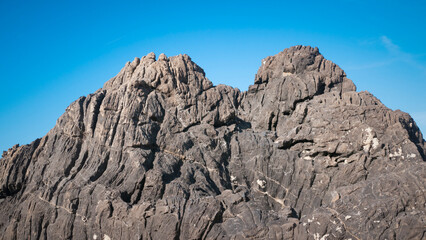Pared de roca oscura con pliegues y arrugas bajo cielo azul