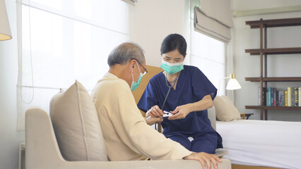 Obraz premium Happy woman nurse, daughter taking a covid test to sick old senior elderly patient lying on bed in bedroom in home in medical. Coronavirus. Asian Thai people lifestyle. Family