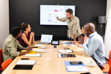 Businessman explaining business strategy to multiracial colleagues in meeting at office