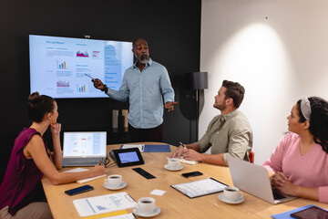 Businesswoman explaining business plan to multiracial colleagues in meeting at office