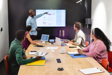 Businessman explaining business plan to multiracial colleagues in meeting at creative office