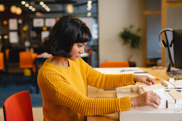 Side view of biracial young female architect examining architectural model in creative office