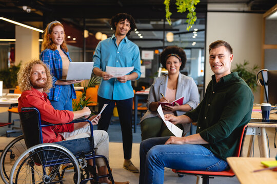 Portrait of smiling multiracial businesswomen and businesswomen in meeting at creative office