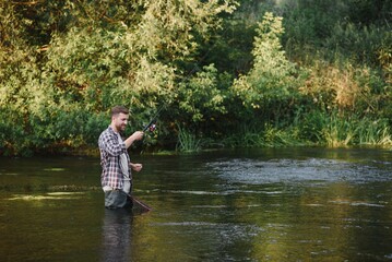 Fisherman catches a trout on the river in summer