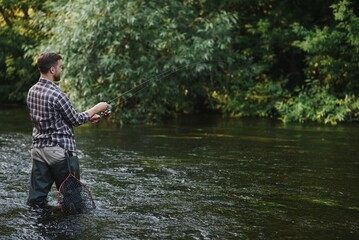 Fisherman catches a trout on the river in summer