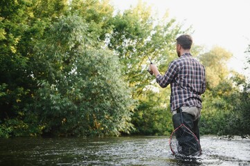 Fisherman catches a trout on the river in summer