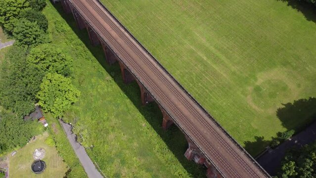 Aerial footage looking down onto an old railway viaduct with a passing train. Drone 4k video. 