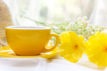 Coffee morning.  Yellow steaming cup of hot coffee for relax after working hobbies crochet on white wooden near window with flowers.