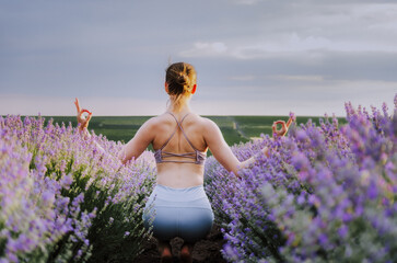 Woman in active wear in a yoga pose with chin mudra gesture, in a lavender field at sunset 