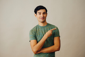 Portrait hispanic latino man pointing to the side at copy space black hair smiling handsome young...