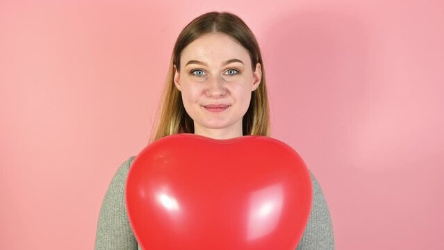 Closeup studio portrait of young female holding heart shaped ballon. St valentines or mother's day.