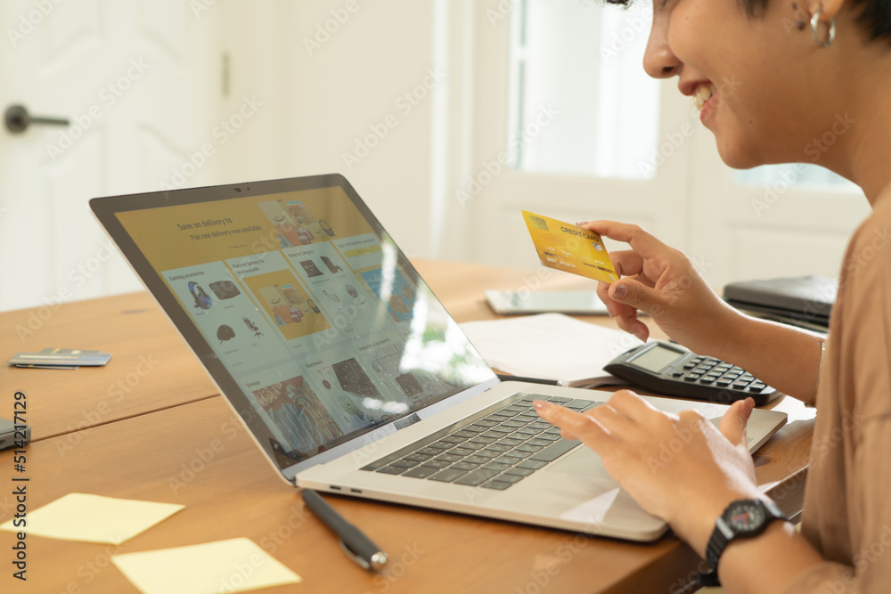 Wall mural Portrait of business Asian woman, person using a credit card, shopping online at home or house, using a computer laptop notebook, technology device. People lifestyle.