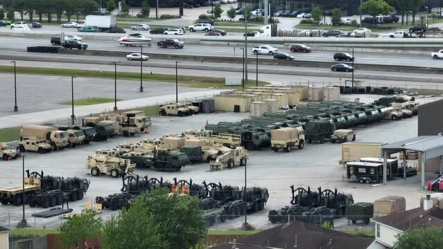 US Army Depot in USA. Camouflaged trucks and tanks ready for battle along interstate freeway highway. American military and defense theme.