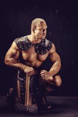 Fototapeta na wymiar Studio shot of muscular ancient warrior man posing with axe