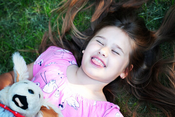 Funny little girl lying on green grass - 514218182