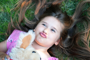 Funny little girl lying on green grass - 514218185