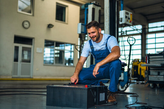 Portrait Shot of a Handsome Mechanic Working on a truck workshop Service. Professional Repairman. Modern Clean Workshop.